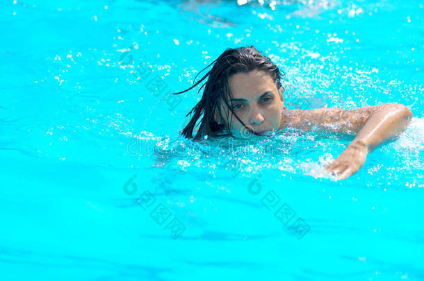 夏天漂亮的年轻女人在游泳池里游泳