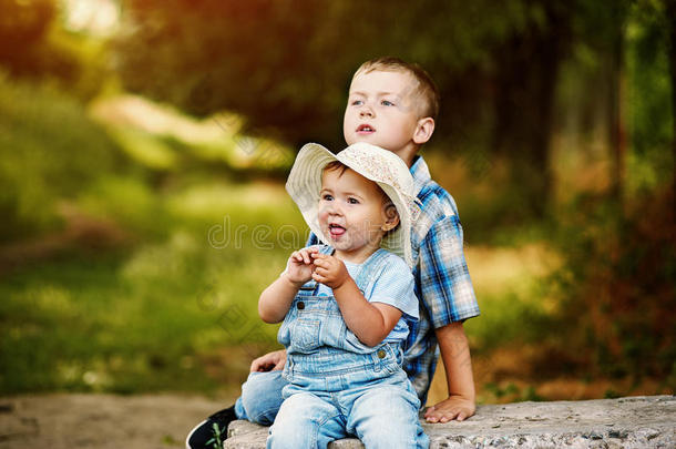 有趣的小女孩和你哥哥坐在公园里
