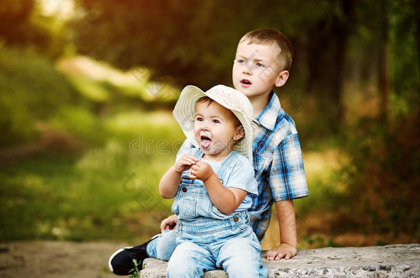 有趣的小女孩和你哥哥坐在公园里