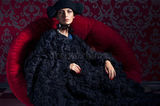 穿着黑色帽子的女人坐在<strong>红色</strong>沙发上的<strong>古典</strong>肖像