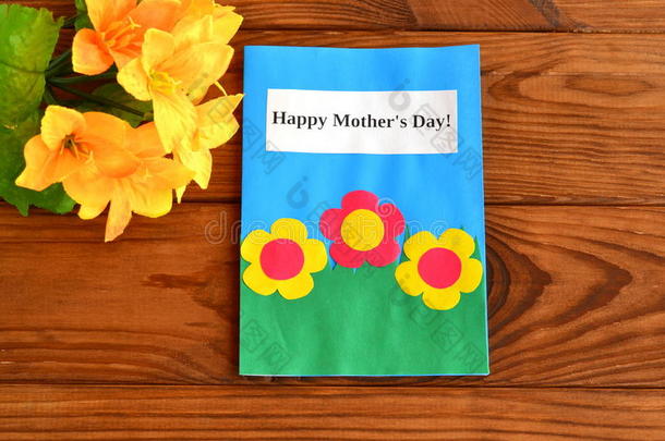 卡片上写着快乐的母亲节。 一束花。 母亲节的儿童工艺品。 木制背景