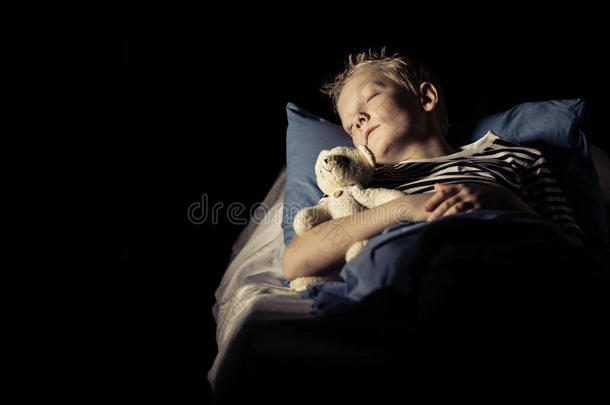 可爱的男孩和毛绒玩具熊睡在床上