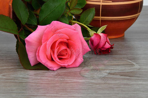 倾覆的花瓶和玫瑰。 水从花瓶里漏出来了。 花瓶是木制的。