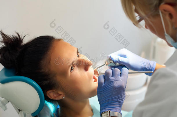 美丽的女牙医在牙科办公室治疗病人的牙齿