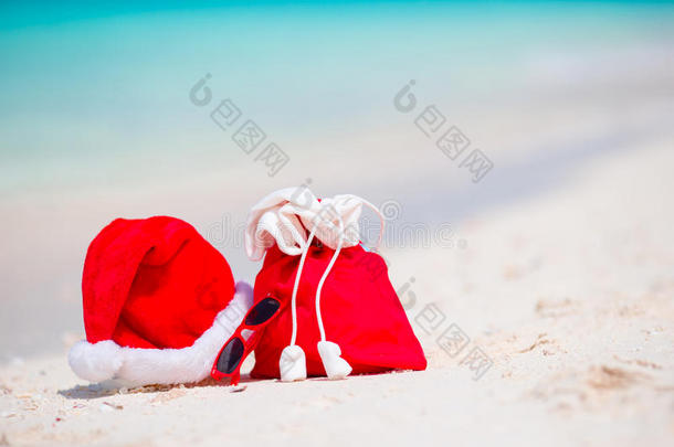 白色海滩上的圣诞配件。 圣诞节旅游度假和旅游概念。 带圣诞老人帽子的海滩配件