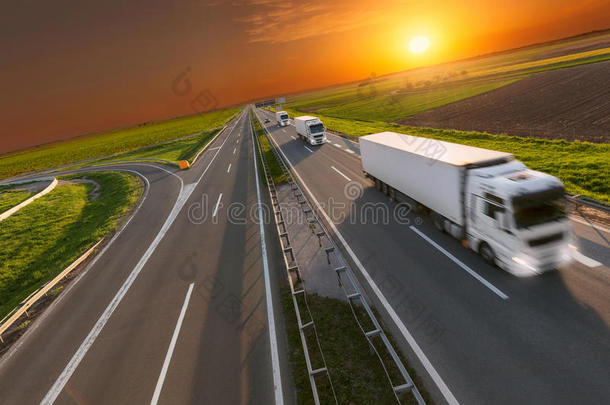 在日落时，在高速公路上运送运输卡车在运动模糊