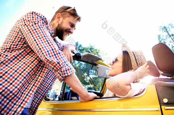 一对敞篷车。 美丽的年轻夫妇在敞篷车上享受公路旅行，微笑着看着对方