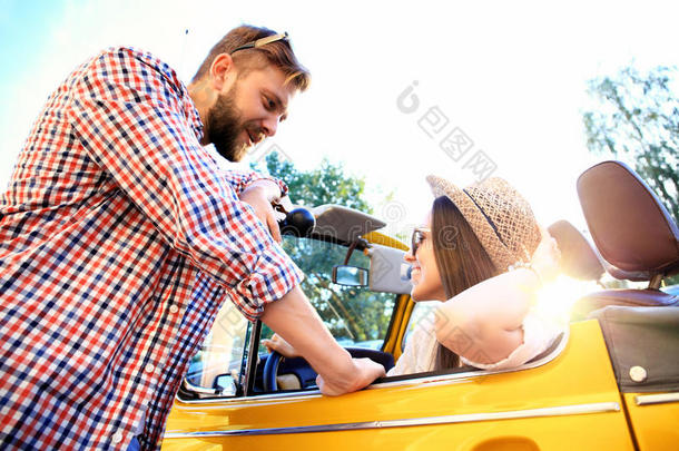 一对敞篷车。 美丽的年轻夫妇在敞篷车上享受公路旅行，微笑着看着对方