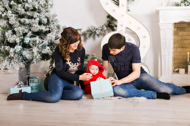 圣诞家庭打开礼物盒，<strong>爸爸妈妈</strong>和<strong>孩子</strong>在装饰的房间里，坐在圣诞树下。