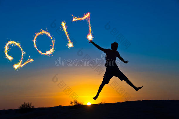 用闪闪发光的2017年，一个男孩在阳光下跳跃的剪影，新年的概念