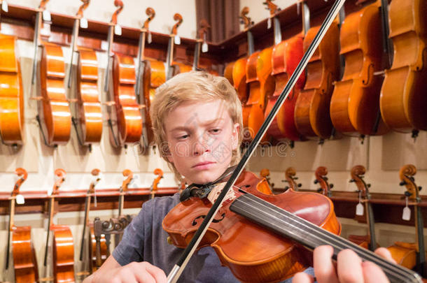 男孩小提琴手在一家音乐商店拉小提琴