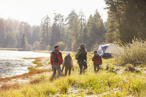 一家人在野营旅行中走在湖边，背景