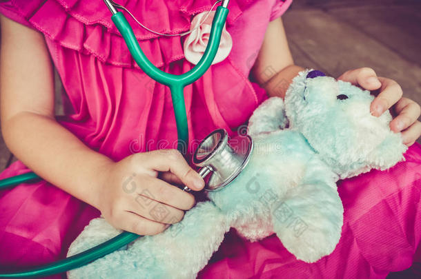 孩子在家里玩医生或护士和毛绒玩具熊。 复古色调效果。