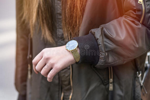 秋季时尚服装。 一个年轻时尚的女人在一个超大轰炸机夹克与金表在手的细节拍摄