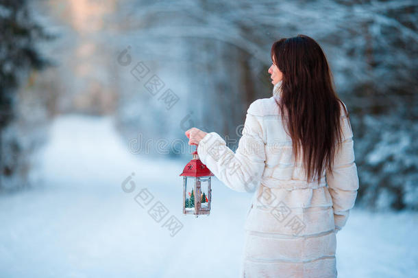 在美丽的冬季雪天，女孩在户外拿着圣诞灯笼