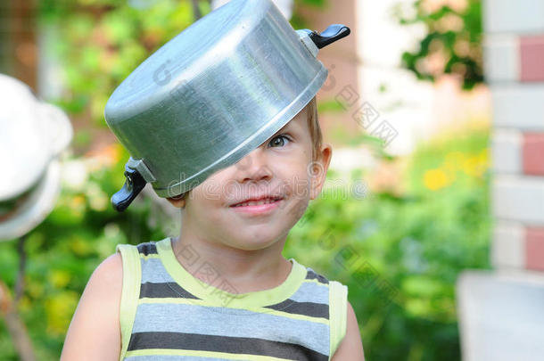 一个头上有平底锅的孩子。 带平底锅的孩子。 快乐的孩子放纵。 一个戴着平底锅帽子的孩子。