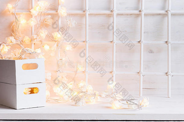 圣诞节柔软的家居装饰，灯光燃烧，盒子在白色的木制背景上。