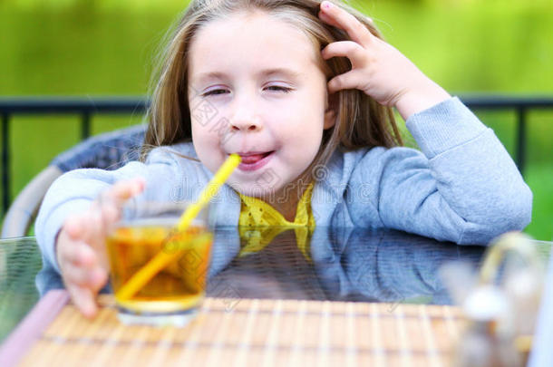 可爱的小女孩在咖啡馆喝苹果汁