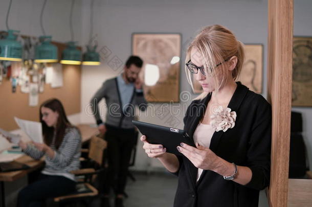 4k。 特写年轻漂亮的金发女商人在现代<strong>创业</strong>办公室使用触摸屏平板电脑。