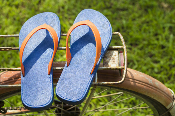 蓝色凉鞋在自行车马鞍与阳光温暖的色调与复制水疗