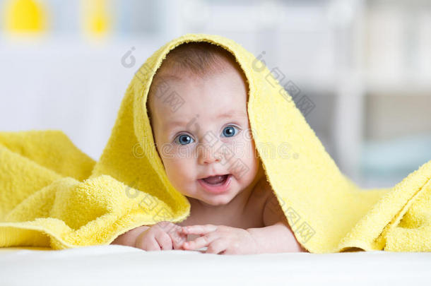 洗澡或淋浴后，婴儿在卧室的毛巾下。 给孩子的纺织品和床上用品