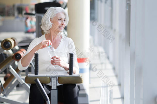 快乐迷人的高级妇女在健身房锻炼时放松。