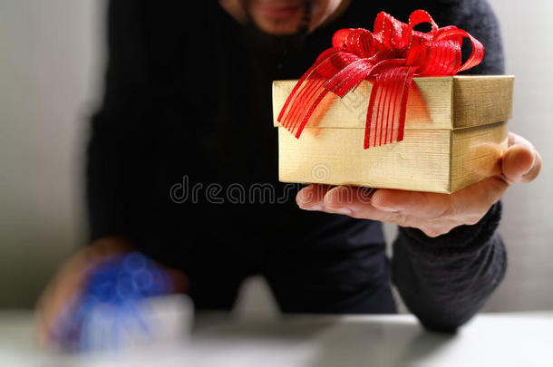 送礼，男人用手拿着礼品盒，以示送礼。模糊的背景，博克效应