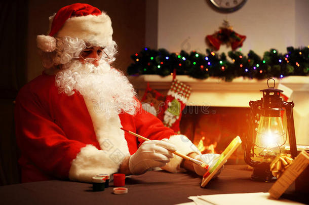 圣诞节的概念。 圣诞老人做玩具，特写。 木制桌子上的圣诞装饰品