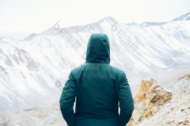 坚定的旅行者双手插在口袋里站着看雪山的场景