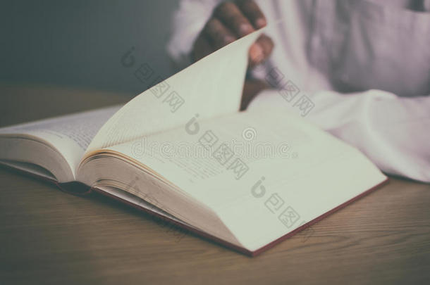 一个男人在桌子上读一本书，一边用老式过滤器<strong>翻页</strong>