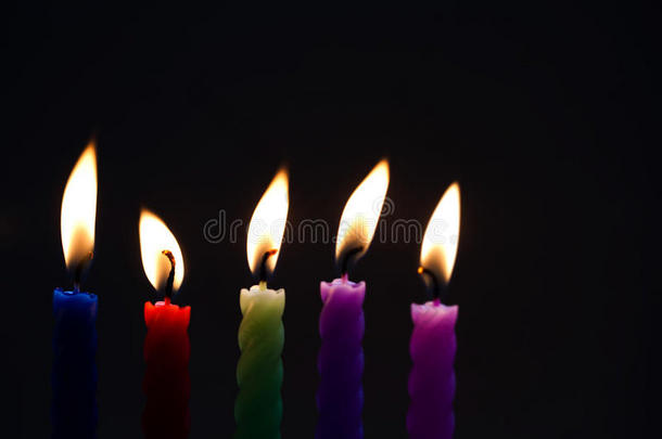 黑色背景上的彩色蜡烛。 蓝色、红色、绿色、紫色、粉红色的蜡烛，有真正的火焰。 柔和的焦点，浅的深度