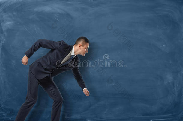 商人站着，好像他要在蓝色黑板背景上跑步或追求他的<strong>目标</strong>。
