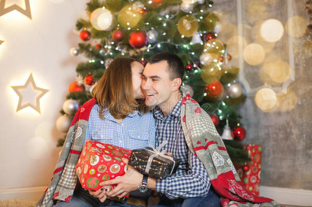 一对相爱的夫妇在圣诞树附近的毯子下互相送礼物