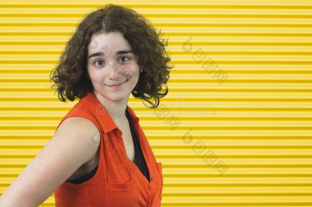 新鲜的年轻女孩，深色头发，黄色条纹背景上穿橙色