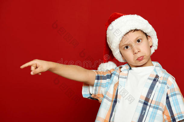 男孩儿童肖像在圣诞老人帽子上的红色，有乐趣和情感，寒假的概念