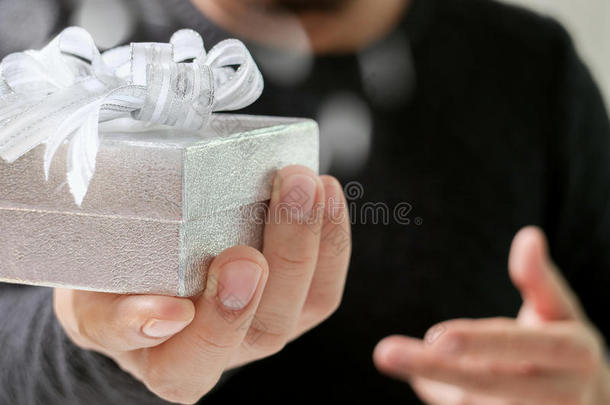 送礼，男人用手拿着礼品盒，表示送礼。模糊的背景，复古的效果
