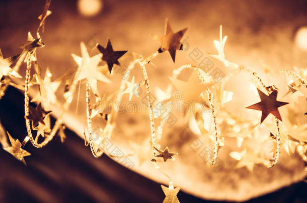 金色闪亮的星星与闪闪发光的圣诞灯在圣诞夜的金色作为豪华的圣诞节背景