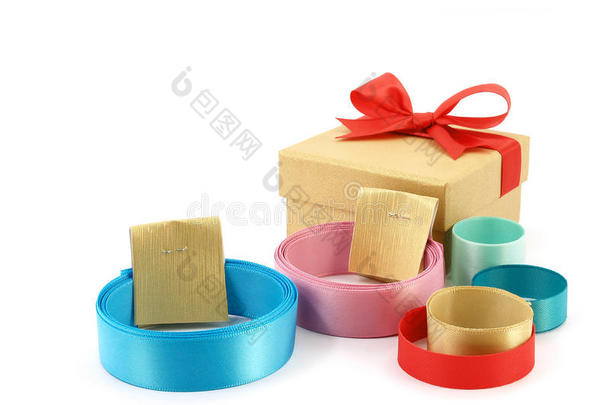关闭一堆彩色卷带与金纸标签带子和金色礼品盒与红色丝带蝴蝶结隔离在白色