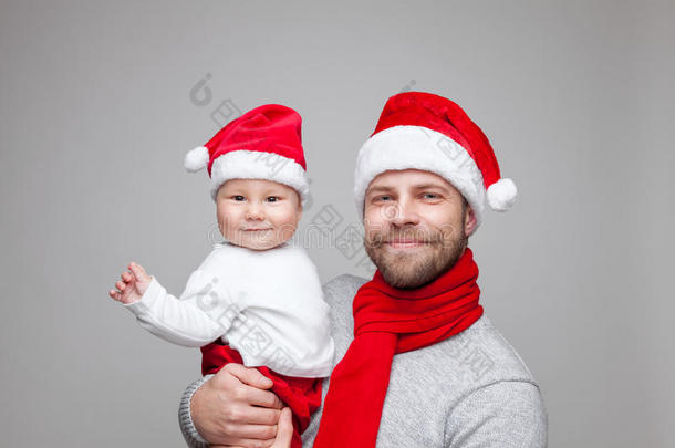 父亲带着小男孩戴着圣诞老人的帽子庆祝圣诞节