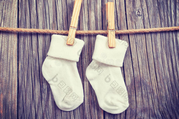 挂在晾衣绳上的婴儿用品。 婴儿白色袜子在衣夹上