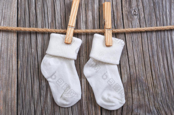 挂在晾衣绳上的婴儿用品。 婴儿白色袜子在衣夹上