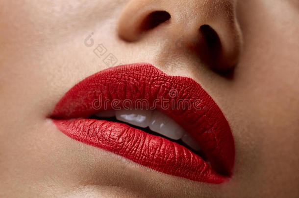 特写美丽的女人嘴唇上涂着红色的口红。 美妆