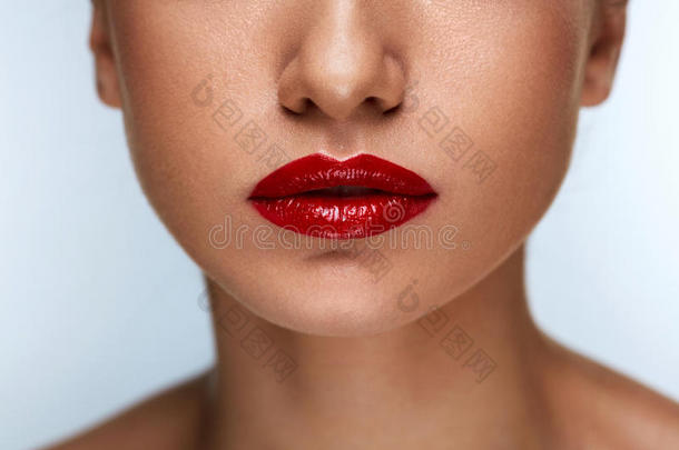 特写美丽的女人嘴唇上涂着红色的口红。 美妆