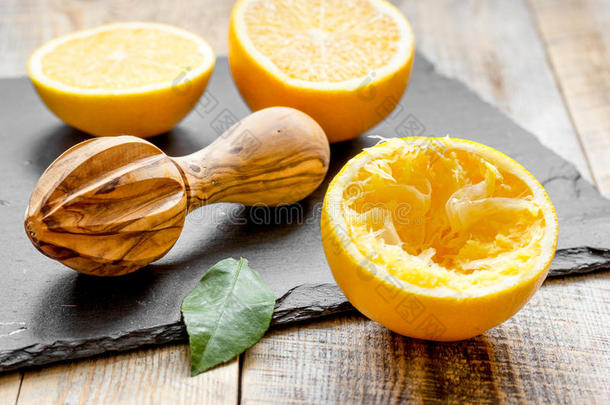 把橘子切成两半，在木制背景上用榨汁机榨汁
