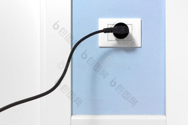 蓝色墙壁上的墙壁插座上的黑色插头