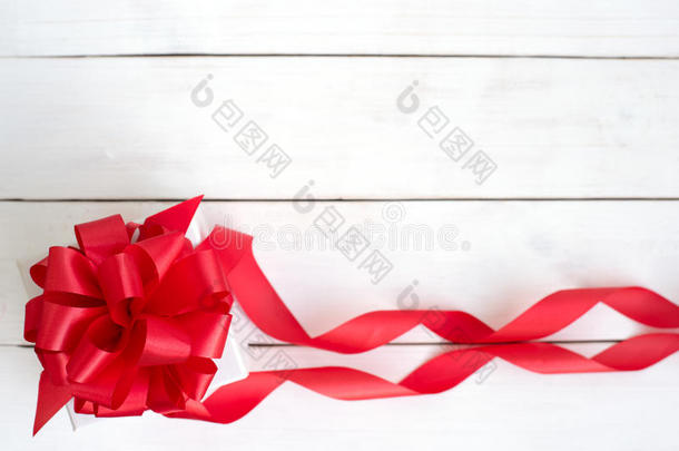 礼品盒，红色丝带蝴蝶结在木制白色背景上