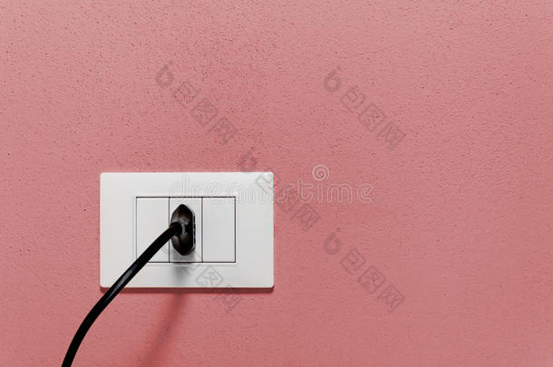 红色墙壁上的墙壁插座上的黑色插头