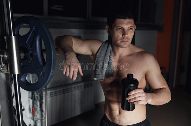 健身者在健身房累了，拿着摇床和运动营养-摇床的蛋白质。