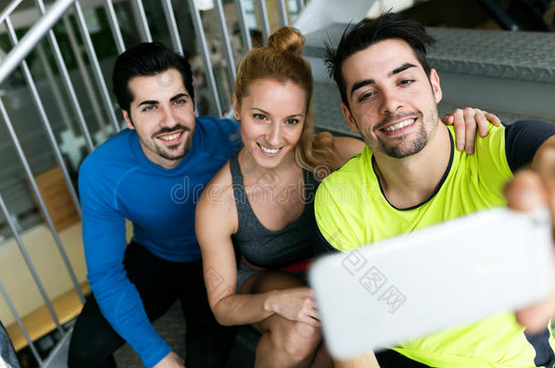一群运动的人在健身房使用手机。