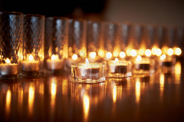 在透明的眼镜里燃烧蜡烛，闪亮的地板，反射。 心情，放松，祈祷和安慰